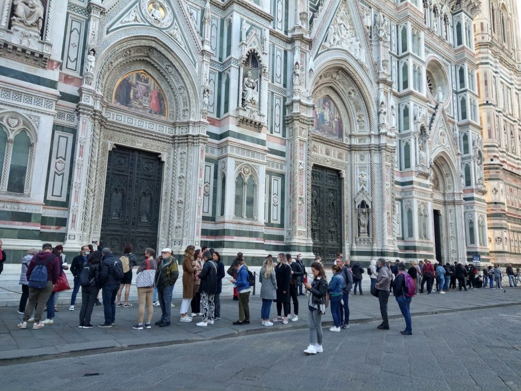 Facciata di Santa Maria del Fiore in Piazza del Duomo a Firenze con una lunga coda di persone in attesa per entrare