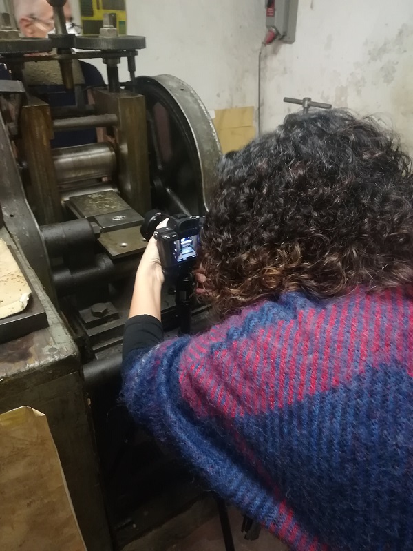 nell'immagine si vede la fotografa valentina braschi che riprende una fase di lavoro degli oggetti metallici nella ditta cecchi di giuliano ricchi in piazza santo spirito a firenze